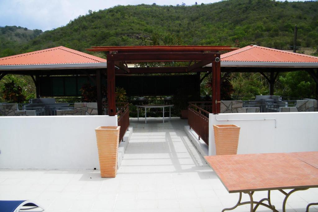 un patio con una mesa y un pabellón con montañas en el fondo en Villa de charme avec piscine MQAA07, en Les Anses-dʼArlet