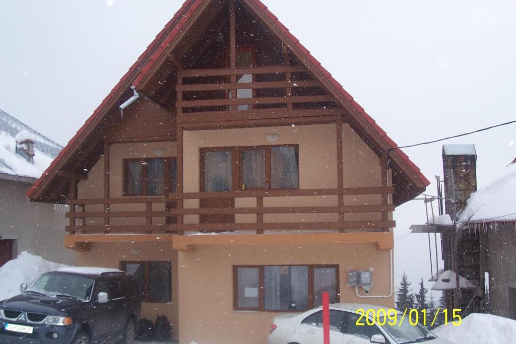 una casa con techo de gambrel en la nieve en Cabana Selena en Ranca