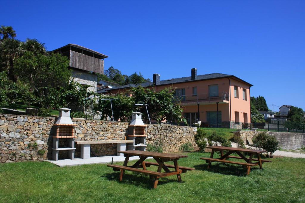 two picnic tables in the grass with a building in the background at Apartamentos Arcos del Esva in Luarca