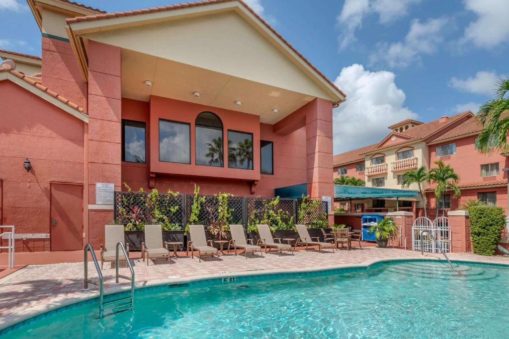 パームビーチ・ガーデンズにあるBest Western Plus Palm Beach Gardens Hotel & Suites and Conference Ctのスイミングプール(椅子付)と建物