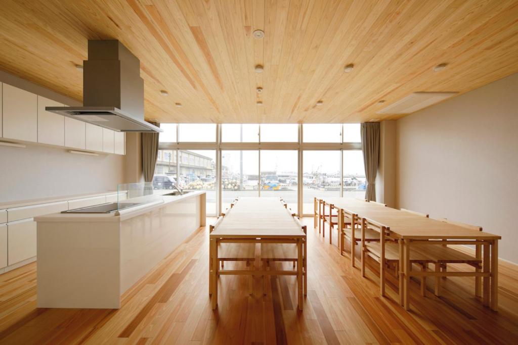 una cocina con techos y mesas de madera y una gran ventana en 渚泊魚津丸, en Motoshin