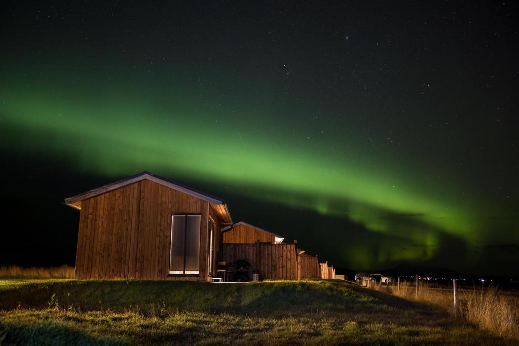a building with a green aurora in the sky at Austurey Cottages in Laugarvatn