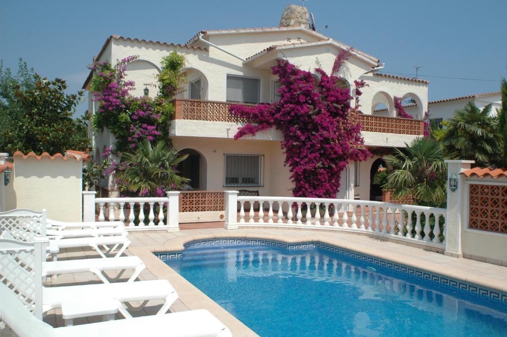 a villa with a swimming pool in front of a house at Villa Sol in Empuriabrava