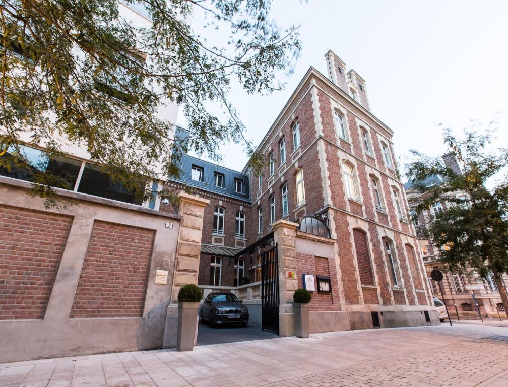 a large brick building with a car parked in front of it at Hôtel Spa Marotte in Amiens