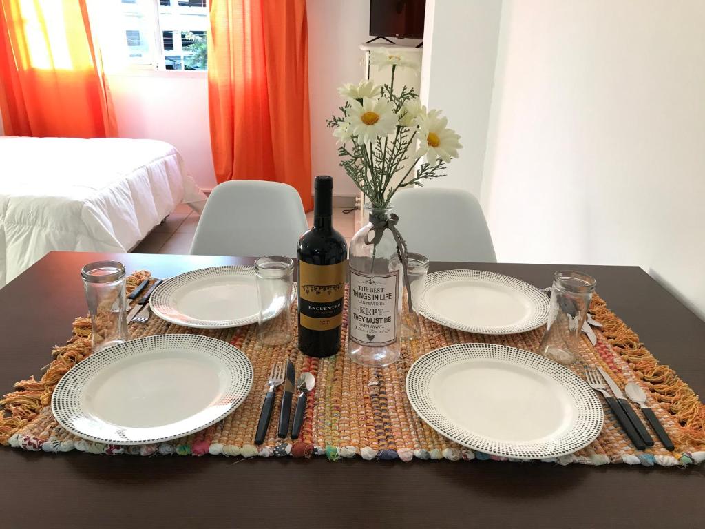 uma mesa com pratos e uma garrafa de vinho e flores em Cares Apartament, Morón, Buenos Aires em Morón
