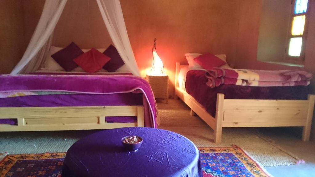una habitación con 2 camas y una mesa en una habitación en Riad Auberge Bassou, en Nkob