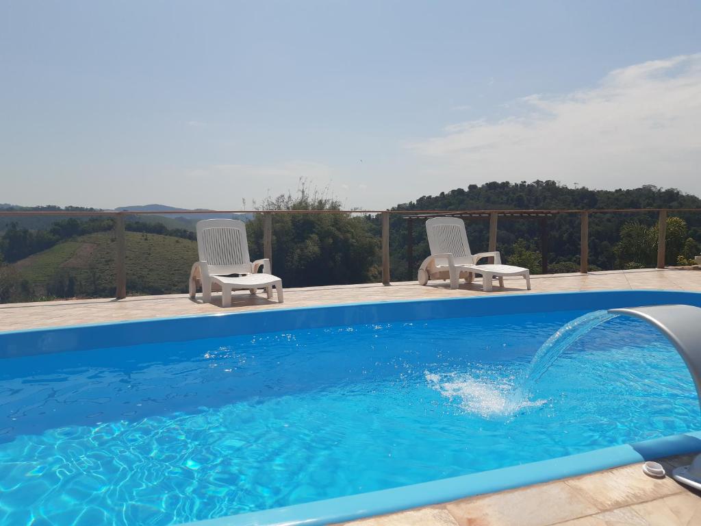 a swimming pool with two lawn chairs and a swimming pool at Restaurante e Pousada Chique na Roça in São Luiz do Paraitinga