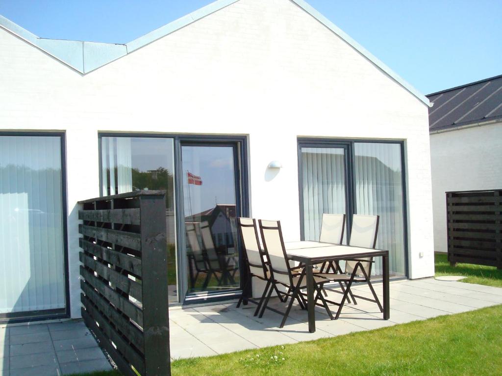 eine Terrasse mit einem Tisch und Stühlen neben einem Haus in der Unterkunft Slettestrandvej Apartment - Slettestrandvej 130 nr. 3 - ID 623 in Slettestrand