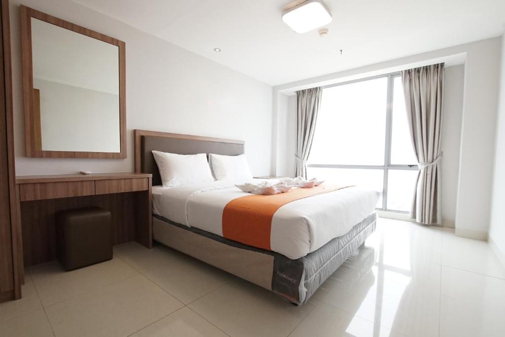 a bedroom with a bed with a mirror and a window at Apatel The Mansion Jasmine Tower Aurora J31J in Jakarta