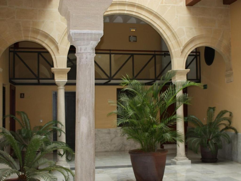 a building with two potted plants in a courtyard at Casa Singular , parking gratis in Jerez de la Frontera