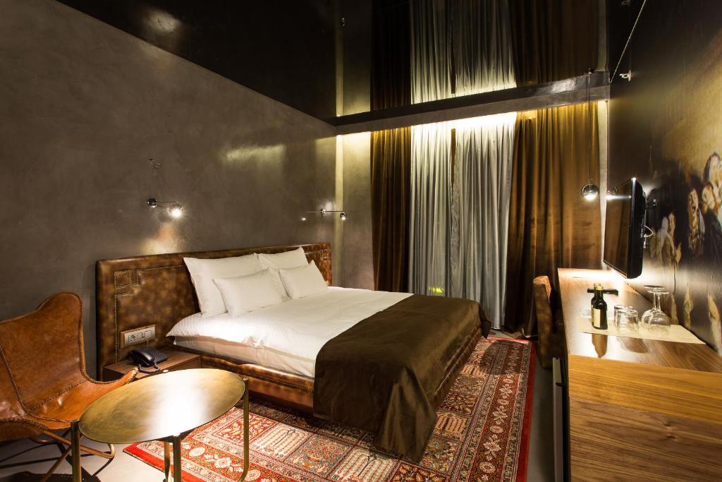 ein Schlafzimmer mit einem Bett, einem Tisch und einem Stuhl in der Unterkunft Hotel Hemera in Podgorica