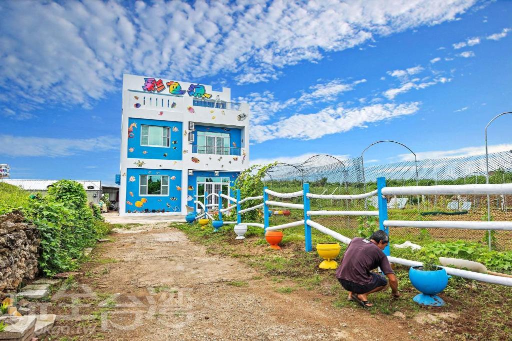 un hombre se agacha delante de un patio de juegos en Penghu Color FIsh Homestay, en Huxi