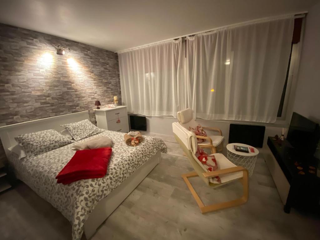 um pequeno quarto com uma cama e uma cadeira em Le Belvédère - GÎTES MARCK em Turckheim