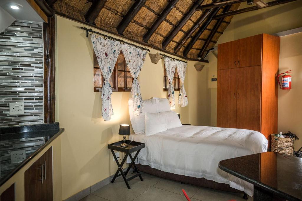 a bedroom with a bed and a window with curtains at Country Rose in Hluhluwe
