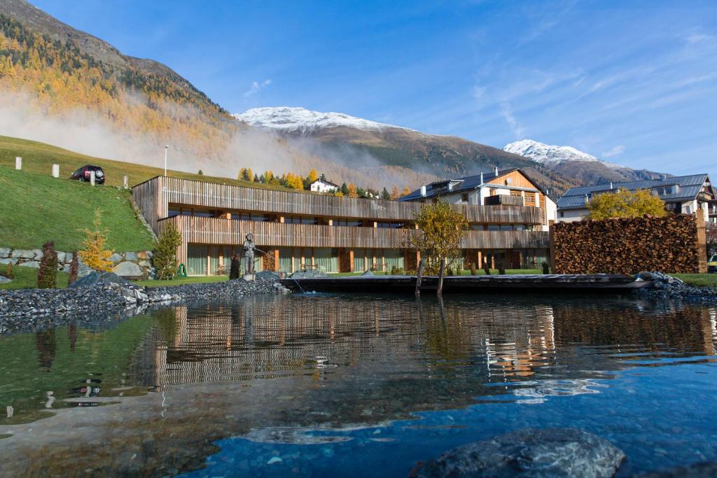 un edificio vicino a un corpo d'acqua con montagne di Relais & Châteaux IN LAIN Hotel Cadonau a Brail