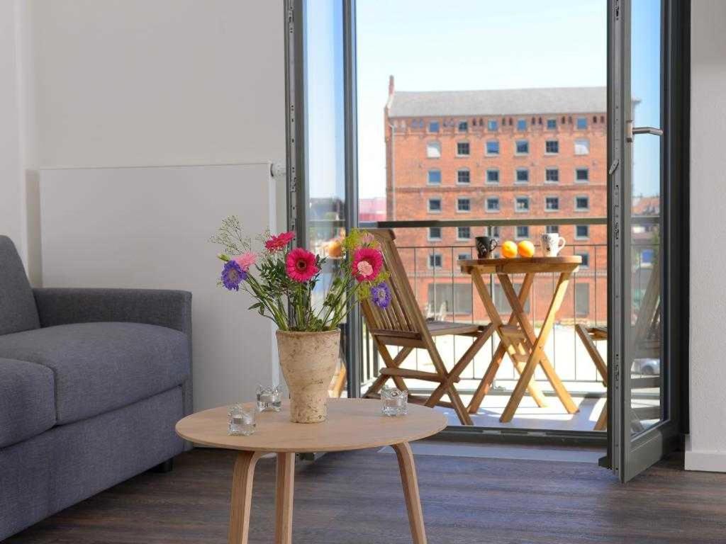 una sala de estar con un jarrón de flores sobre una mesa en Ohlerich Speicher App_ 10, en Wismar