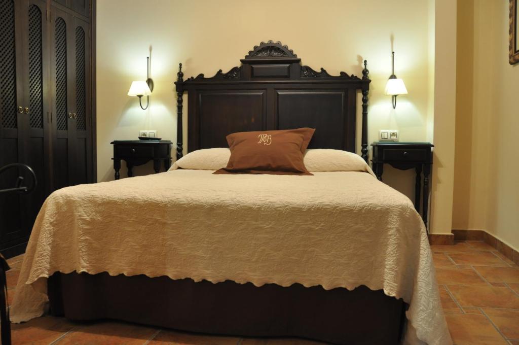 a bedroom with a large bed with a wooden headboard at Apartamentos Turisticos Doña Maria La Brava in Plasencia