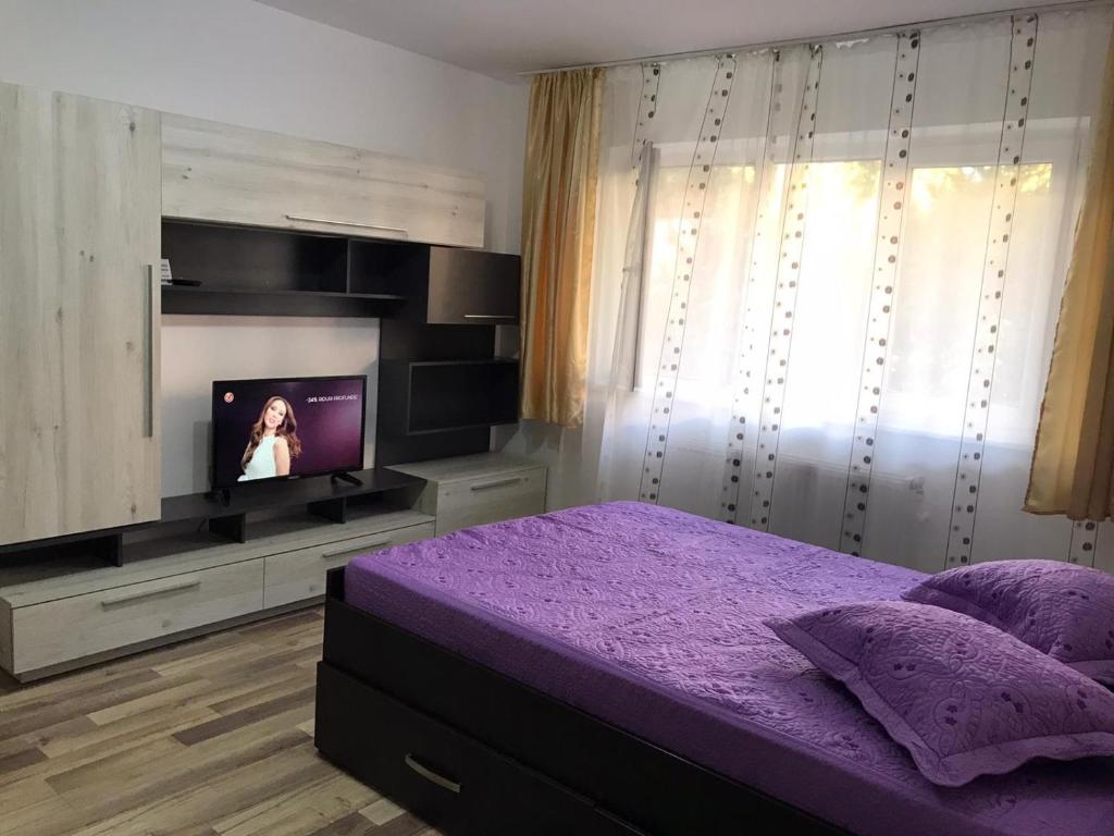 a bedroom with a purple bed and a flat screen tv at Apartament Untold in Turda
