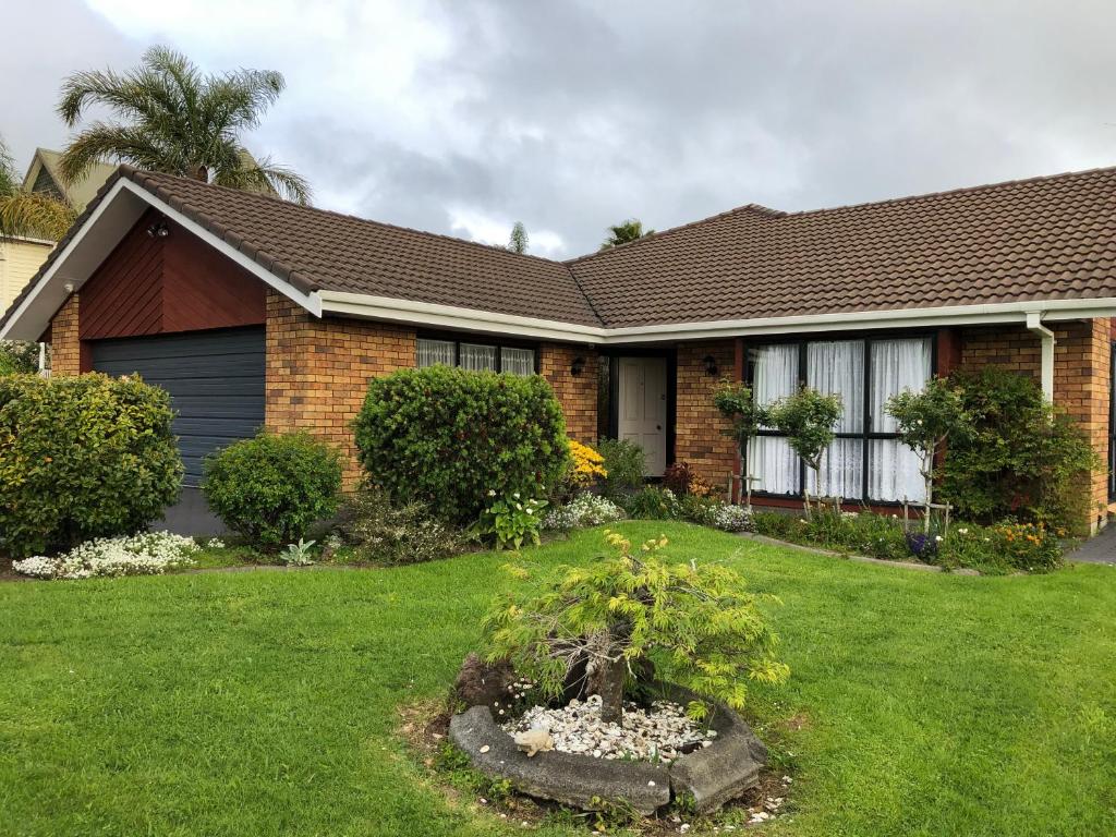 uma casa com um jardim no quintal da frente em The Gardens' Treasure em Auckland