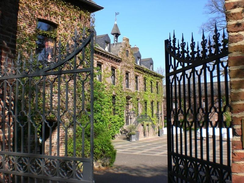 ein eisernes Tor vor einem Gebäude mit Efeu in der Unterkunft Burg Wegberg Hotel & Eventlocation in Wegberg