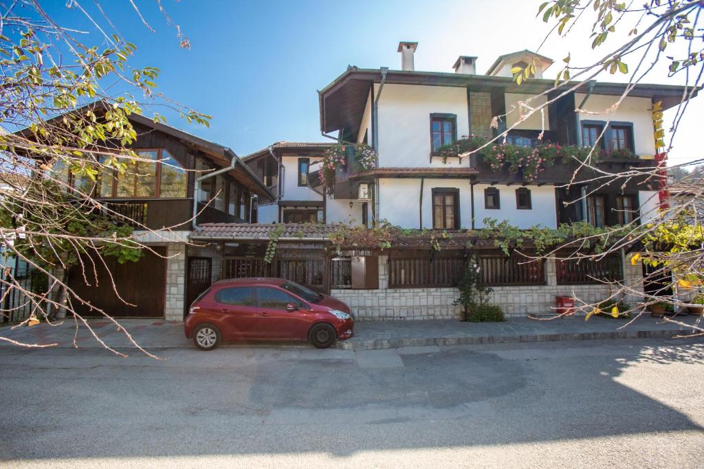 a red car parked in front of a house at Oazis Family Hotel in Lovech