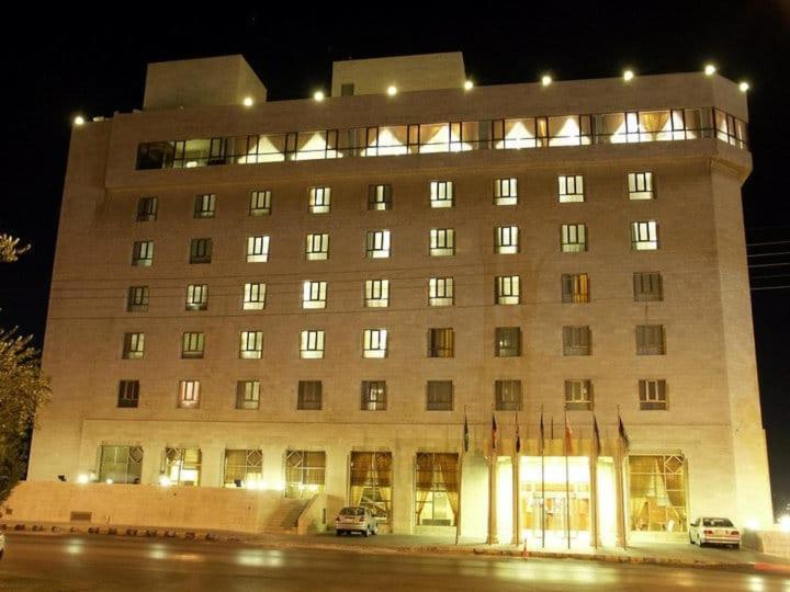 ein großes Gebäude mit davor geparkt in der Unterkunft Le Vendome Hotel in Amman