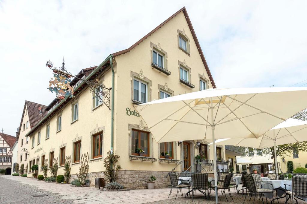 a building with tables and umbrellas in front of it at Hotel Gasthof Krone in Niederstetten