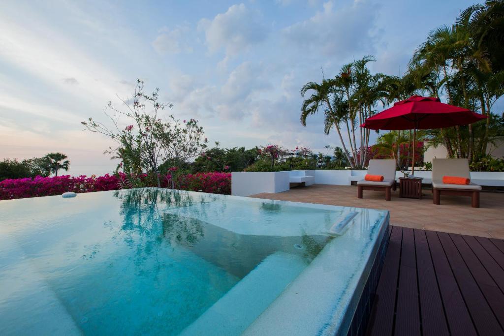ein Pool mit einem Sonnenschirm auf einer Terrasse in der Unterkunft Ocean views Kata gardens penthouse 6C in Kata Beach