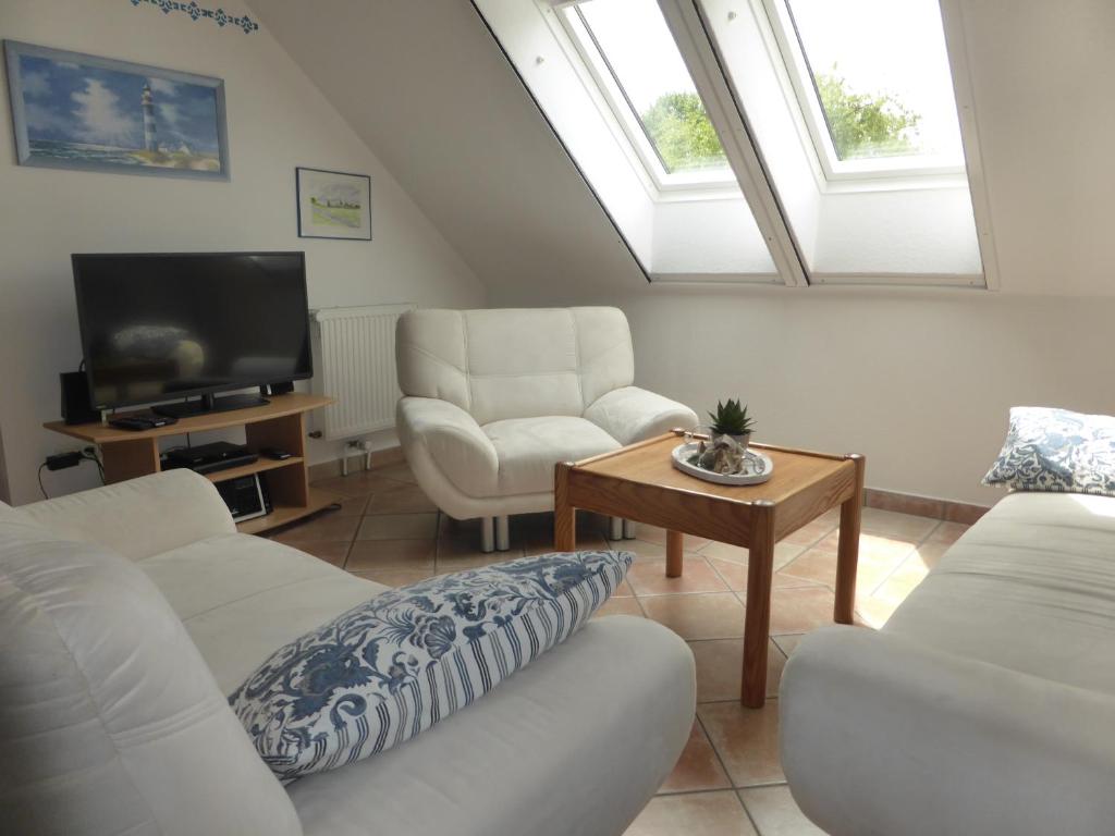 a living room with two white couches and a tv at Friesenwohnung in Norden