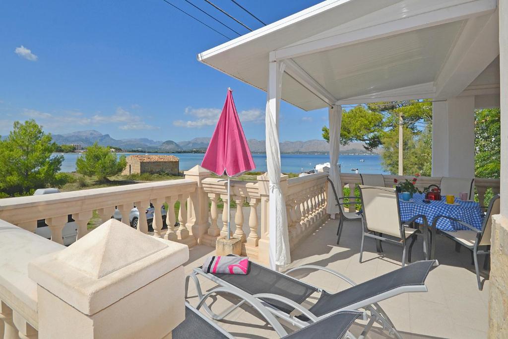 une terrasse couverte avec des chaises, une table et un parasol rose dans l'établissement Apartment Sunset, à Alcúdia