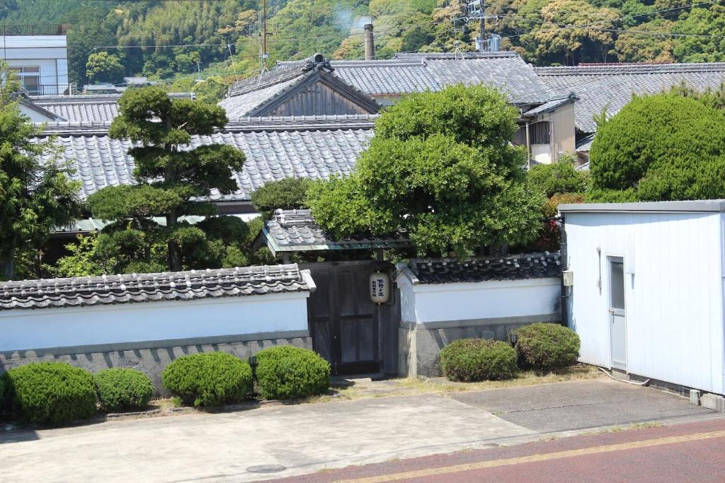 uma imagem de uma casa com um portão e arbustos em Guest House Wagaranchi Kai em Kumano