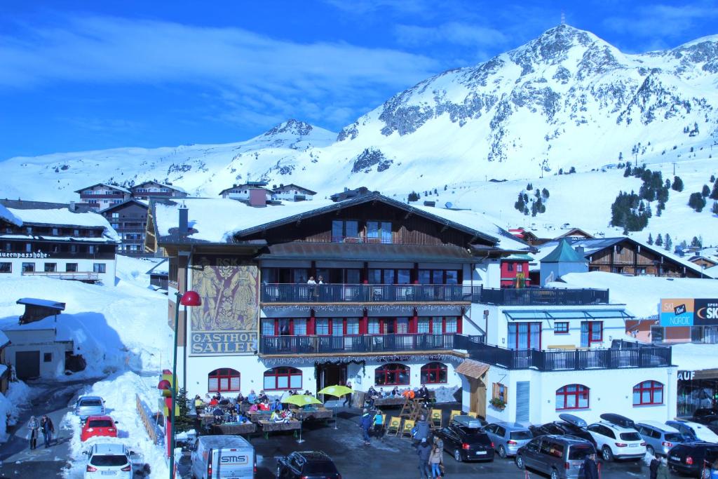 un grand bâtiment avec une montagne enneigée en arrière-plan dans l'établissement Der Sailer Hotel & Restaurant, à Obertauern