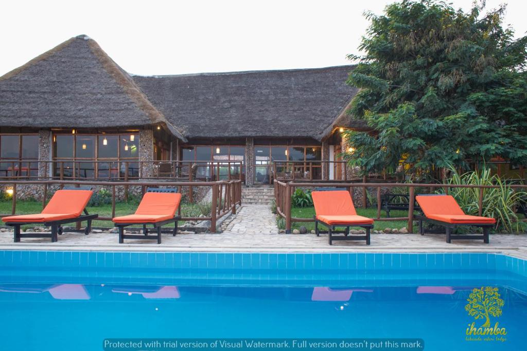 a resort with orange chairs next to a swimming pool at Ihamba Lakeside Safari Lodge in Kahendero