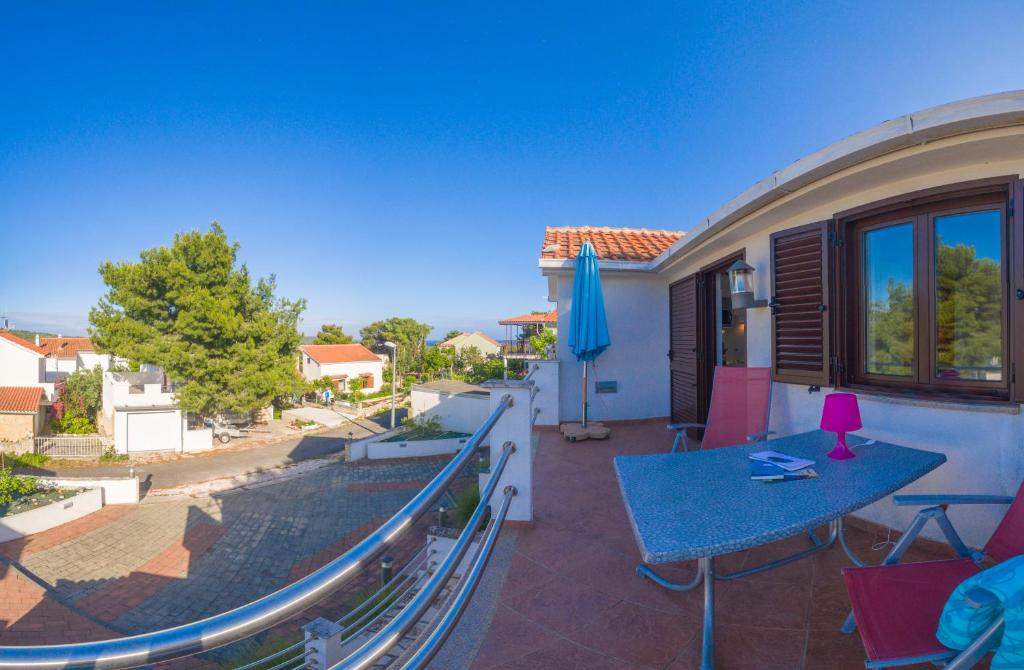 a balcony with a table and a blue umbrella at The Sea House Apartments in Vis