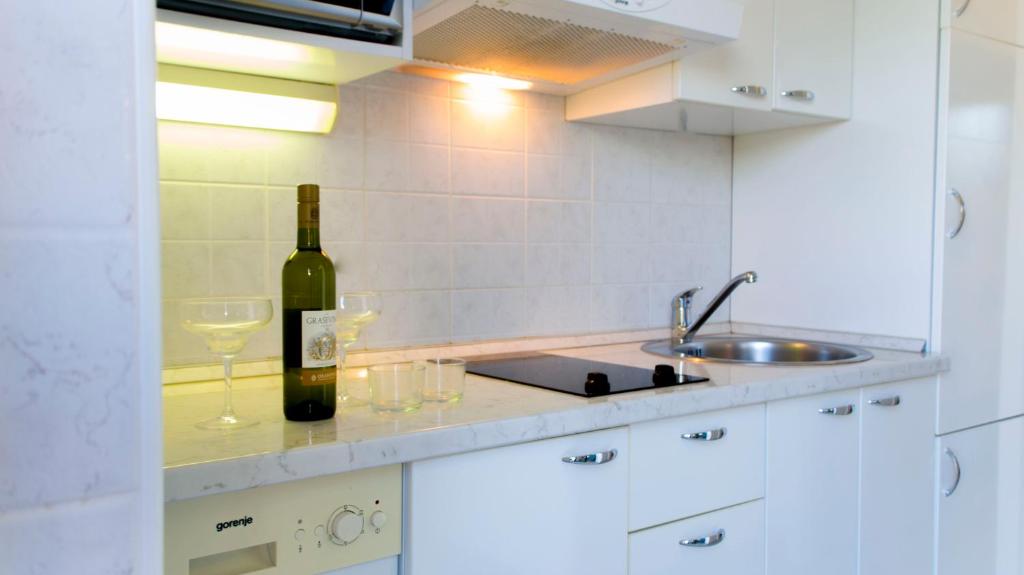 a bottle of wine and glasses on a kitchen counter at The Sea House Apartments in Vis