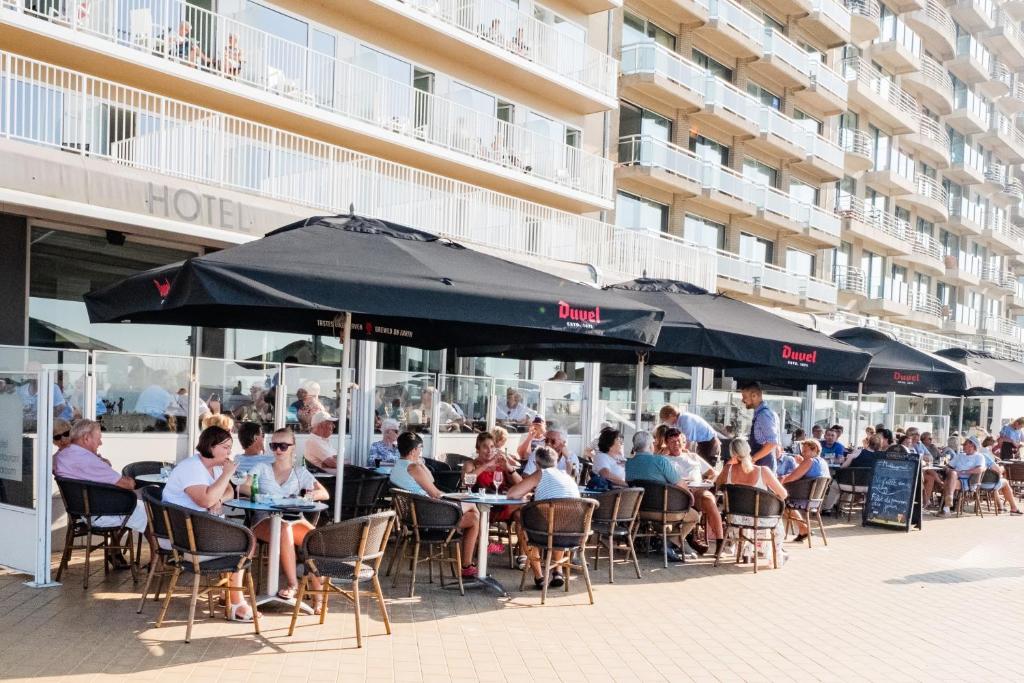 people sitting at tables outside of a restaurant at Hotel Sandeshoved Zeedijk in Nieuwpoort