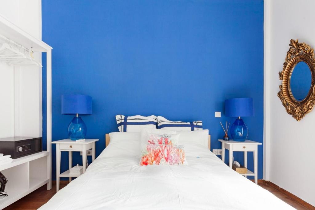 a blue bedroom with a white bed and blue walls at Retropolitan Living Athens in Athens