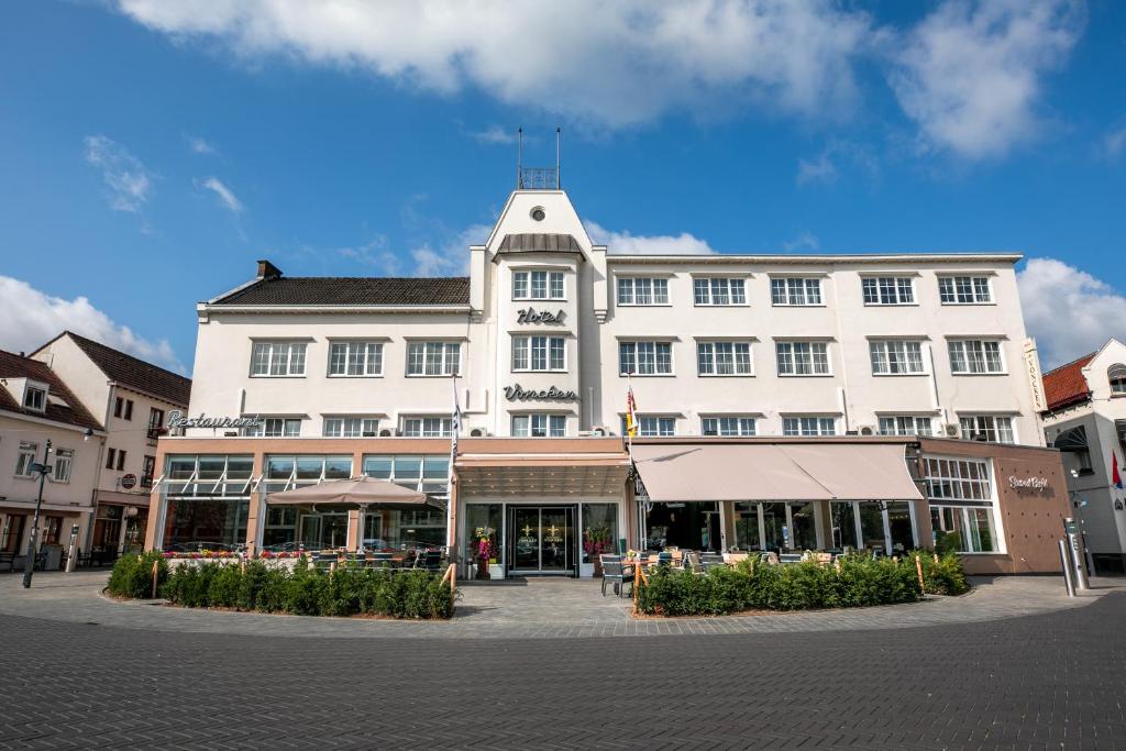 een groot wit gebouw in een stadsstraat bij Hampshire Hotel – Voncken Valkenburg in Valkenburg