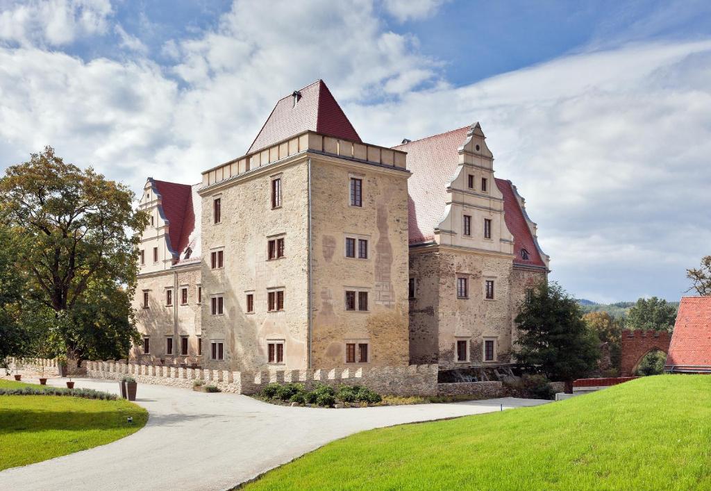 a large building with a tower on a grassy hill at Uroczysko Siedmiu Stawów in Gola Dzierżoniowska