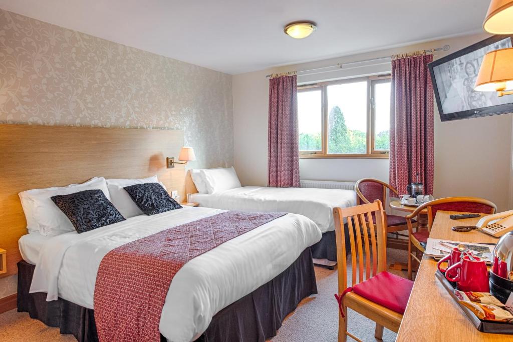 a hotel room with two beds and a desk at Bagden Hall Hotel in Scissett