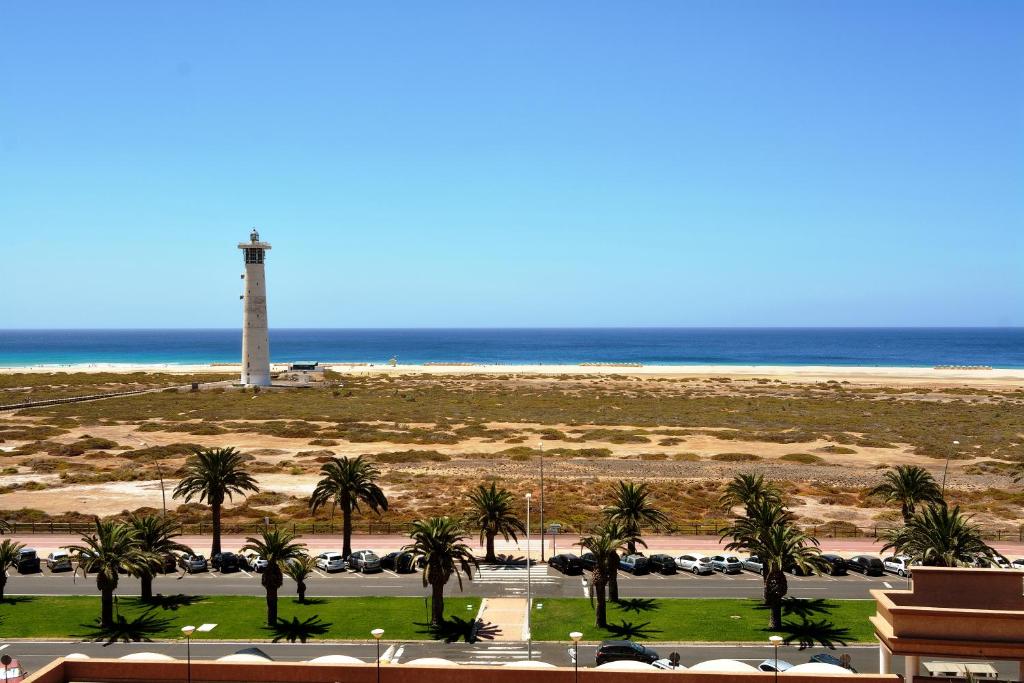 Blick auf den Strand und den Leuchtturm in der Unterkunft The Real Casa Atlantica Morro Jable By PVL in Morro del Jable