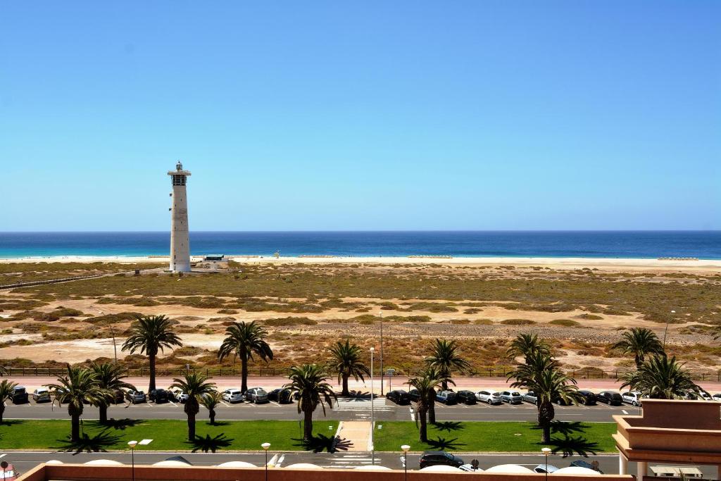 - une vue sur la plage et un phare dans l'établissement The Real Casa Atlantica Morro Jable By PVL, à Morro del Jable