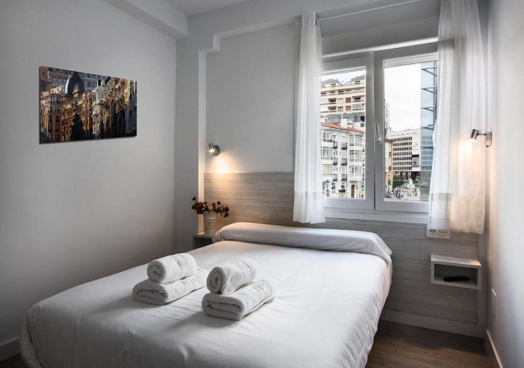 a bedroom with a white bed with towels on it at Hostal Lar in Burgos