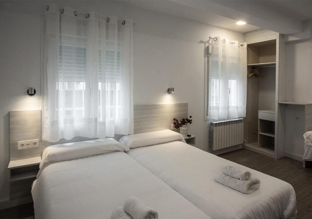 Un dormitorio con una gran cama blanca con toallas. en Hostal Lar, en Burgos
