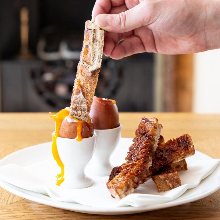 a person holding a piece of food on a plate at Crown Hotel in Southwold