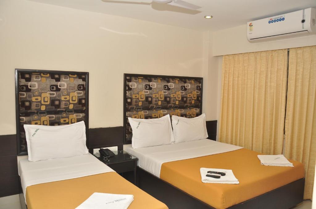 a hotel room with two beds and a window at City Home in Chennai
