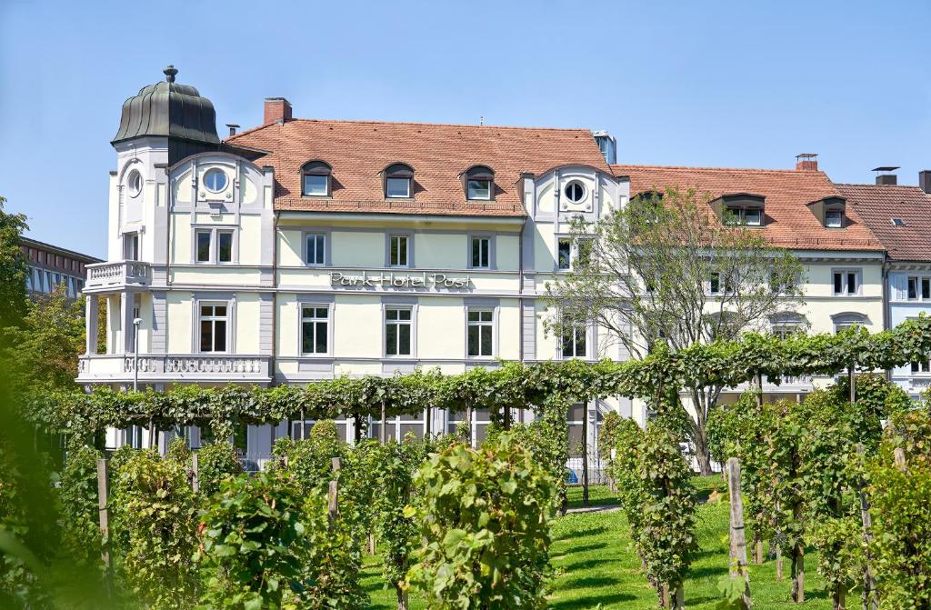 un grand bâtiment blanc avec un toit dans l'établissement Park Hotel Post, à Fribourg-en-Brisgau