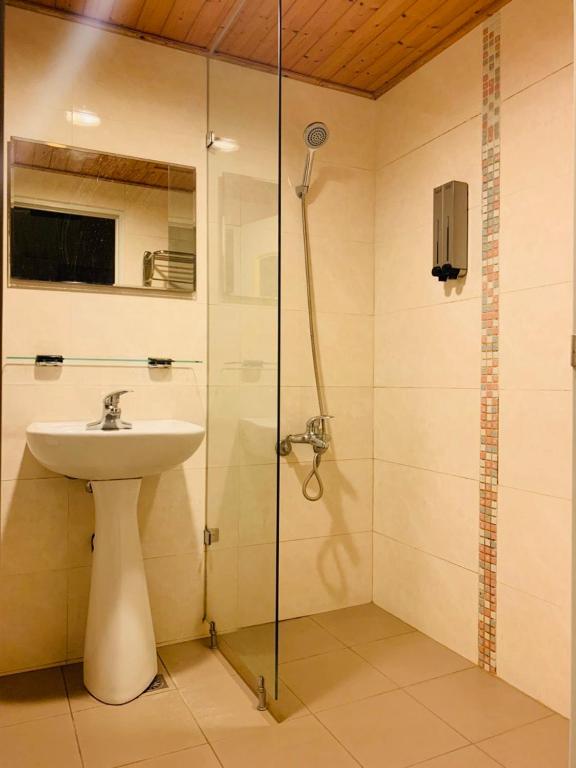 a bathroom with a sink and a glass shower at EasyInn Hotel &amp; Hostel in Tainan