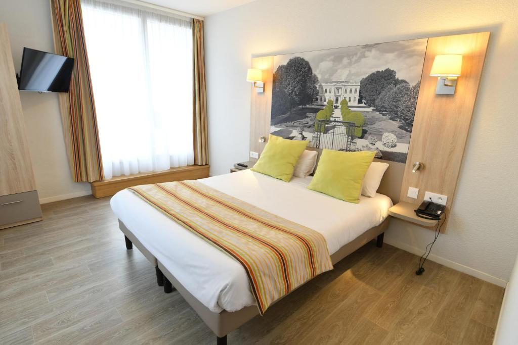una camera d'albergo con un grande letto con cuscini gialli di Appart-Hôtel Mer & Golf City Bordeaux Bassins à flot a Bordeaux