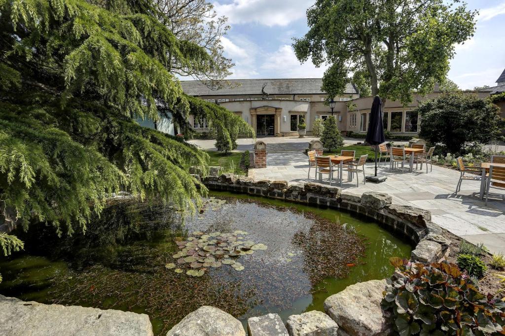 a pond in front of a building with tables and chairs at B/W Premier Doncaster Mount Pleasant Hotel in Doncaster